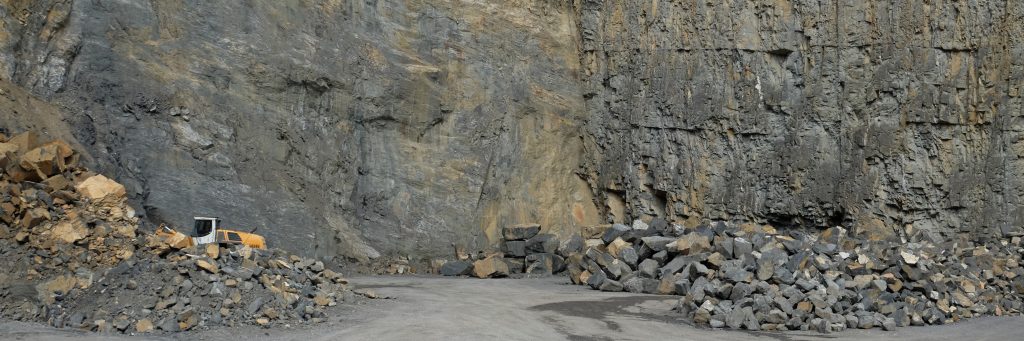 Felswand des Steinbruchs in Ruggell mit Haufen von formwilden Steinen
